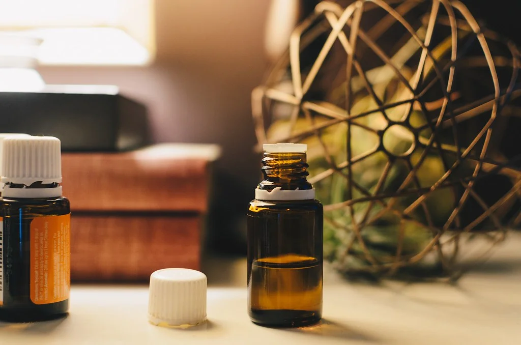 Flacon d'huile essentielle ambré ouvert posé sur une table, en aromathérapie